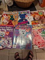 Six Mary Beth's Beanie World magazines showing various Beanie Babies on surrounding surfaces.
