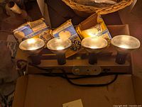 Photo of four metal light fixtures with lampshades attached to a metal bar with electrical cord.
