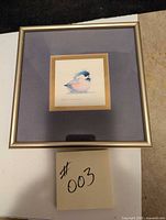 Full front view of framed watercolor painting showing the bird, gold frame, and purple matte.