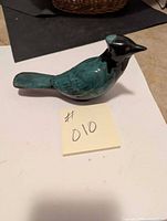 Top side view of the ceramic bird figurine showing teal body and black head and beak.