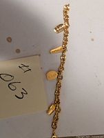 Full view of the gold-tone Avon charm bracelet with multiple Avon charms attached showing length and charm details.