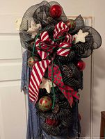 Front view of the Christmas wreath showing decorative ribbons, star ornaments, pine cones and spherical ornaments