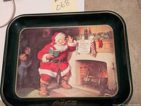 Full view of the metal Coca Cola tray featuring Santa Claus drinking a glass of Coca Cola near a fireplace with two children watching.