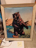 Full view of framed felt bear picture sized 18x22 inches with mountainous lake scene background.