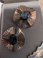 Photo showing close-up view of both earrings focusing on the abalone center and engraved silver design.