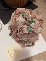 Top view of vintage flower hat showing densely packed brown and gray fabric flowers with green fabric leaves.