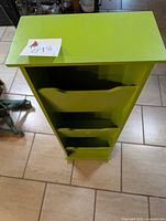 Front view of the tall green wooden magazine rack showing the three slots.