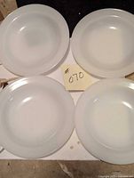Four white round Fireking milk glass bowls placed in a square arrangement, showing size and shape.