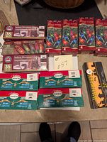 Top-down view of 7 sets of 35-light indoor miniature light strands in original boxes and 5 sets of 20-light strands in original packaging laid on table.