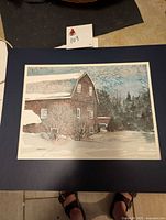 Unframed signed print of brown barn scene with snow, showing full print mounted on dark mat, includes visible signature and edition number.