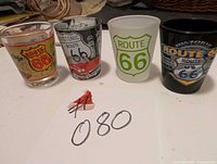 Four Route 66 shot glasses lined up showing front designs
