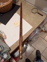 Full length of the carved wooden walking stick with brass knob resting on tabletop