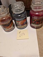 Three Yankee Candle jars on a surface: Salted Caramel, November Rain, and Red Apple Wreath, with a note showing #015.