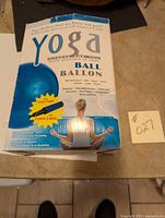 Front view of the yoga ball packaging showing product details such as benefits for fitness, the included hand pump, and image of a woman meditating.