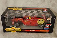 Photo of the die cast model in its original box showing the left side of the red 1999 Reynard CART car with detailed sponsor decals and packaging design.