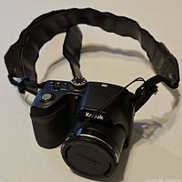 Front angle view of Kodak Easyshare Z5010 camera showing lens with cap attached and padded strap.