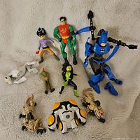 Wide shot showing all assorted action figures including Batman, Robin, Ben 10 character, and others on a light background.