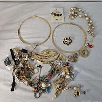 Lot of assorted jewelry items including two gold-tone choker necklaces, pearl strand necklace, and pile of mixed costume jewelry parts and charms.