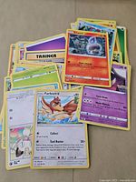 Top view of assorted Pokémon cards with visible Litwick and Farfetch'd cards on top.