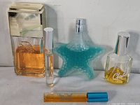 Five vintage women's perfume bottles displayed on a white surface showing different shapes and designs.