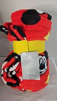 Rolled fleece throw blanket showing Mickey Mouse print and attached Disney tag.