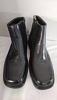 Front view of both black leather boots, showing squared toes and smooth finish.