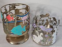 Photo showing two decorative metal 3-wick candle holders, one with an underwater fish design and one with bunnies and flowers