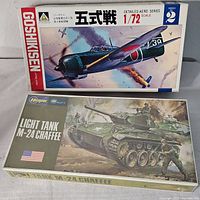 Box tops of the two model kits: detailed aero series Japanese fighter plane in 1/72 scale and M24 Chaffee light tank model kit.