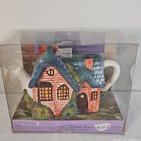 Front view of Thomas Kinkade cottage teapot in original packaging.