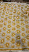 View of entire quilt showing repeating yellow and white hexagonal floral pattern.
