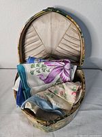 Photo of the vintage decorative box containing folded floral handkerchiefs inside the pleated interior