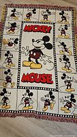 Full view of vintage Mickey Mouse tapestry blanket showing filmstrip border with multiple Mickey poses.