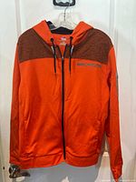 Orange Denver Broncos full zip hoodie by Majestic displayed on hanger, showing front side with zipper, hood, and chest logo.
