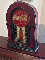 Full front side view of the Coca-Cola AM/FM radio showing the red and black casing and stained glass style front panel with Coca-Cola logo and bottle.