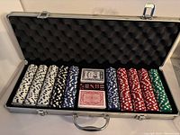 Full poker set arranged inside aluminum carrying case showing all poker chips, decks of cards and dice