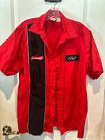 Red Dale Jr bowling style shirt hanging on hanger with visible collar, buttons, and short sleeves. The shirt features a large black vertical panel on the left side front.