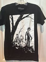 Front view of the black Edward Scissorhands T-shirt featuring a white graphic of the character and a mansion near a tree.