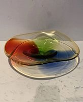 Front angle showing the multicolor hand blown glass bowl with smooth curves and red, green, and blue tones merging with a translucent amber base.