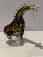 Side view of the hand blown glass giraffe figurine showing amber and clear glass with detailed spots and clear head features