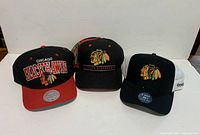 Three Chicago Blackhawks hats and one Team Canada adjustable hat shown from front.