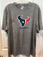 Gray Houston Texans T-shirt with central logo and visible JJ Watt autograph on chest.