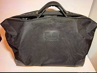 Front view of black Tonino Lamborghini travel duffel bag showing embossed leather logo patch and fabric material.