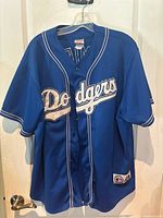 Front view of blue Los Angeles Dodgers baseball jersey with scripted Dodgers logo on front.