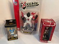 NFL collectible figures of Michael Vick, Jimmy Garoppolo, and Justin Herbert shown together in original packaging.