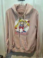 Front view of pink hoodie with Sailor Moon character graphic and Japanese text.