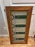 Full view of the stained glass window panel with natural wood frame, showing geometric colored glass design.