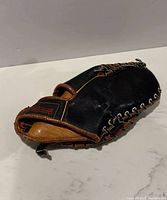 View of Mastercraft 3 Finger Baseball Glove showing black leather with tan trim and red branding on wrist patch.