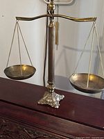 Full view of vintage brass balance scale showing central column, hanging pans, and ornate base