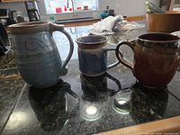 Front view of three handmade pottery mugs on counter