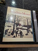 Front cover of Grandma Moses book showing title, author, artwork, ruler for scale